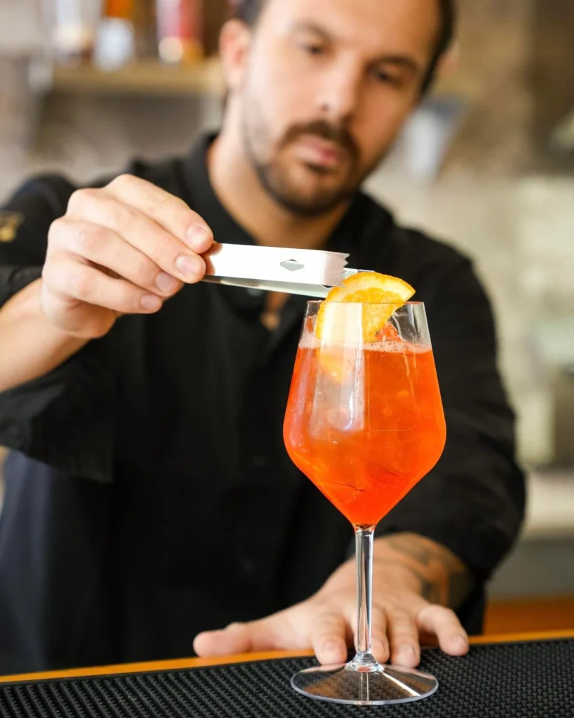 Barman guarnisce uno spritz con fetta d'arancia al bar di Dimora Giulia