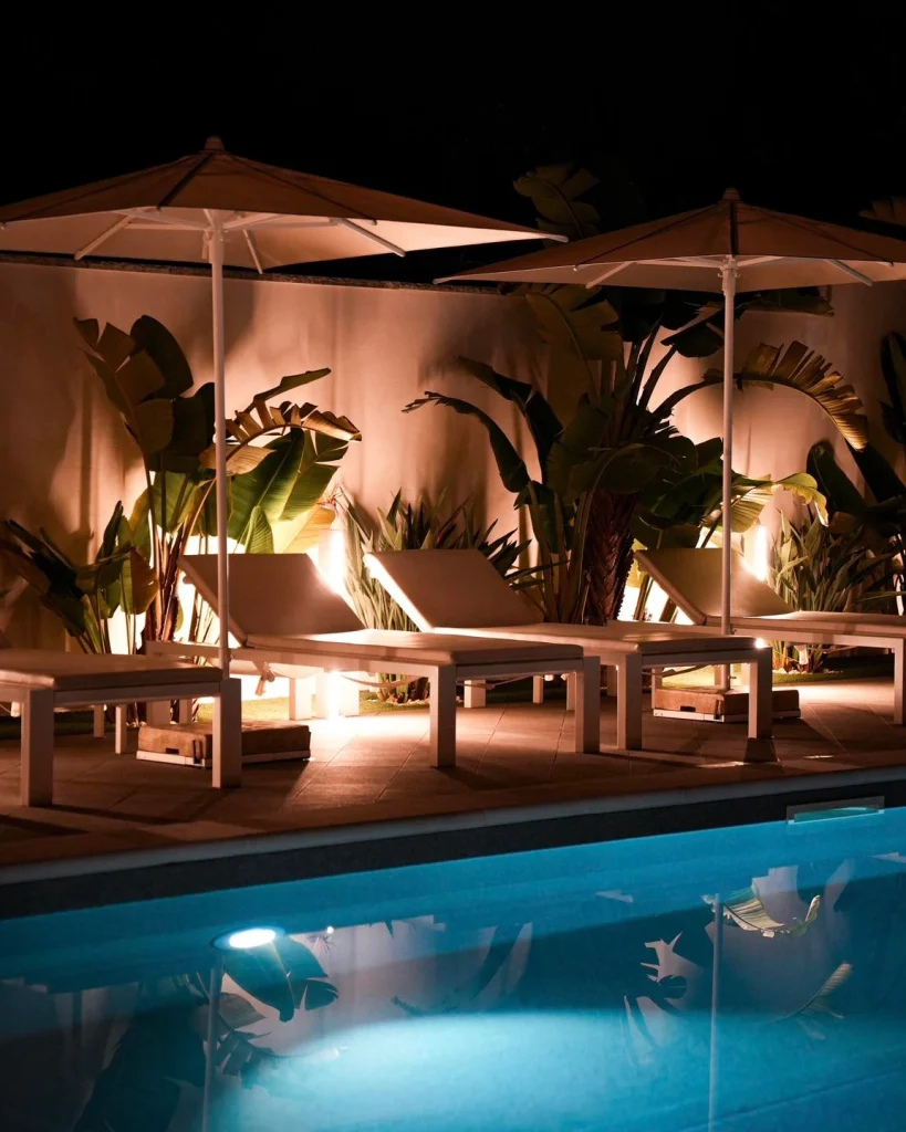 Piscina illuminata di sera con lettini e ombrelloni a Dimora Giulia