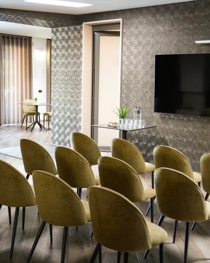 Sala riunioni con TV e sedute verdi per eventi aziendali a Bari