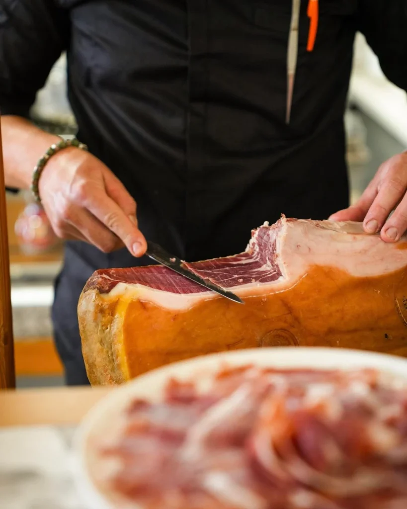Taglio a mano del prosciutto crudo durante un evento a Bari