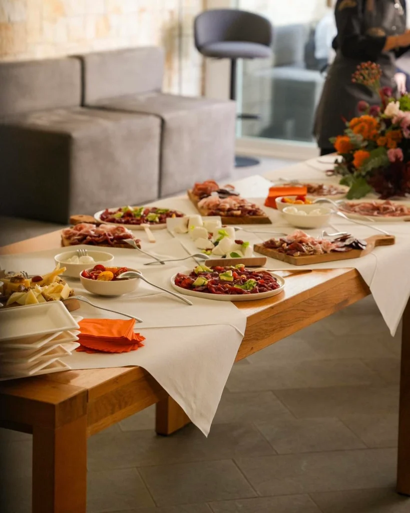 Tavolo buffet allestito con taglieri e fiori nella sala eventi